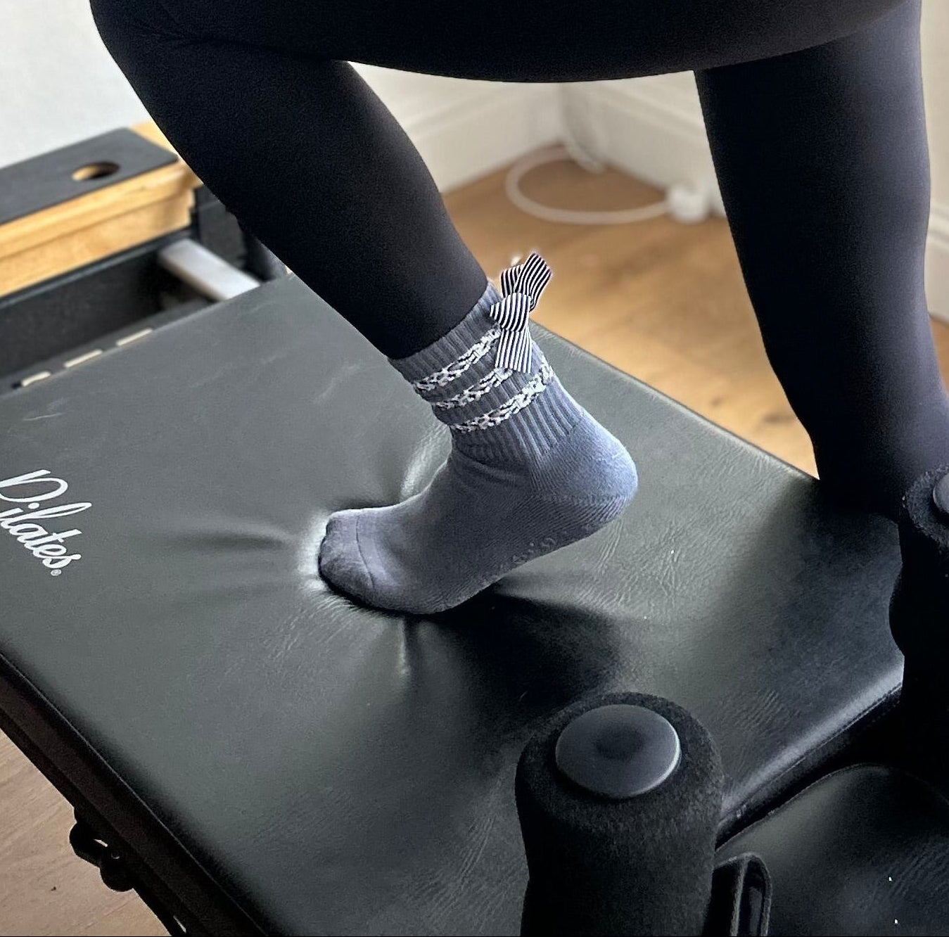 Gray sock with a striped bow on a reformer box